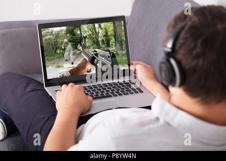Man wearing headphone playing shooting game on laptop Stock Photo