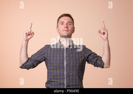 Surprised young man pointing up with two hands. Hey look up concept Stock Photo