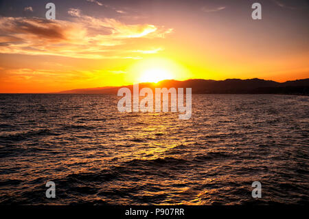 The sun setting over the mountains on the west coast at Santa Monica California and the Pacific Ocean. Stock Photo