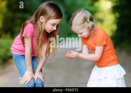 Two adorable little girl catching babyfrogs on warm and sunny summer day Stock Photo