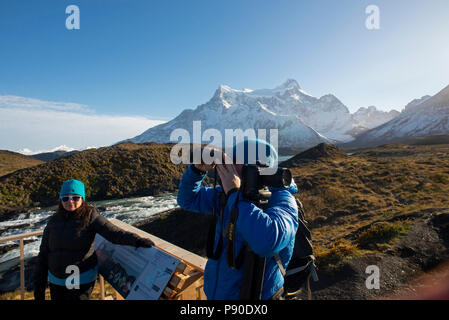 Tourists standing on viewing platform close to. the Salto Grande waterfall with Paine Grande mountain in the background. Stock Photo