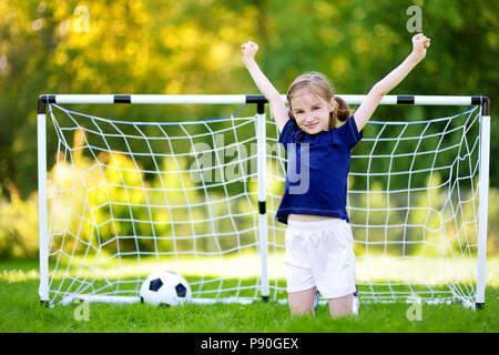 Cute little soccer player having fun playing a soccer game on sunny summer day Stock Photo