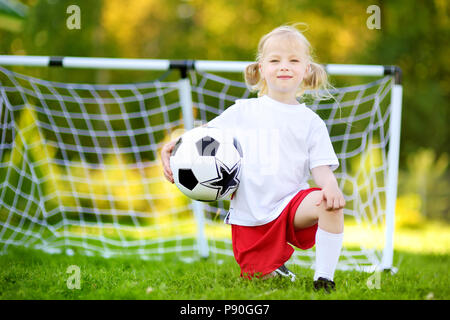 Cute little soccer player having fun playing a soccer game on sunny summer day Stock Photo