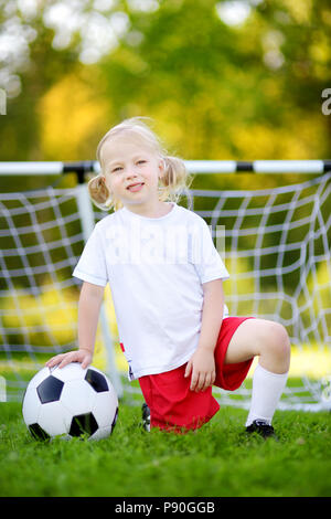 Cute little soccer player having fun playing a soccer game on sunny summer day Stock Photo