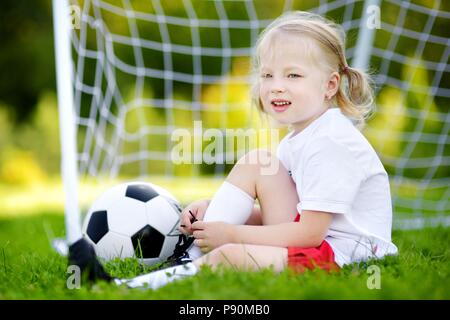 Cute little soccer player having fun playing a soccer game on sunny summer day Stock Photo