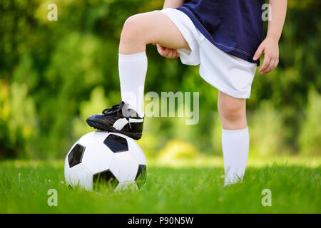 Close-up of a child having fun playing a soccer game on sunny summer day. Sport activities for children. Kids in sports uniform. Stock Photo