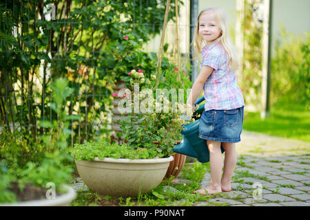 Cute little girl watering flowers in the garden at summer day Stock Photo