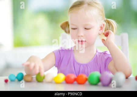 Cute little girl having fun with colorful modeling clay at a daycare. Creative kid molding at home. Child play with plasticine or dough. Stock Photo