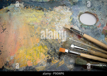 Oil paint of different colors on a palette and brushes Stock Photo