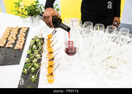 Waitress Pouring Red Wine in Glasses at Buffet Table with White Cloth Stock Photo