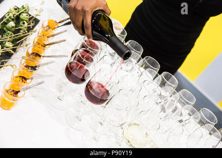 Waitress Pouring Red Wine in Glasses at Buffet Table with White Cloth Stock Photo