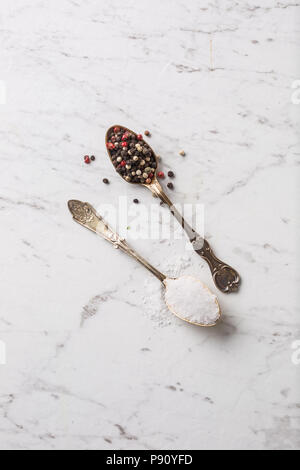 Salt and pepper in spoon on white marble board. Stock Photo