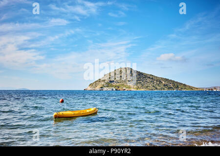 Rabbit island and a yellow canoe on the sea in Bodrum Gumusluk Mugla Turkey on a bright sunny day Stock Photo