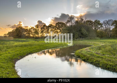 Sunset over meandering creek in small river valley in Drenthe, Netherlands Stock Photo