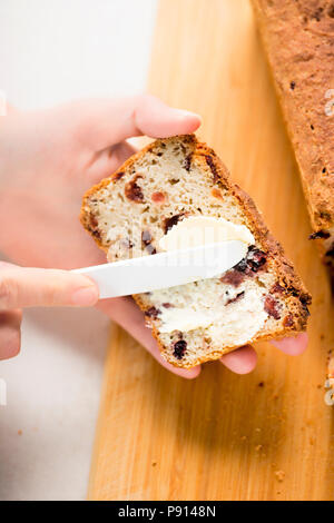 Woman spreading butter on slice of sweet cranberry bread Stock Photo