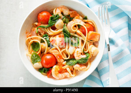 Seafood linguine with prawns, scallops and salmon, spinach and tomatoes Stock Photo