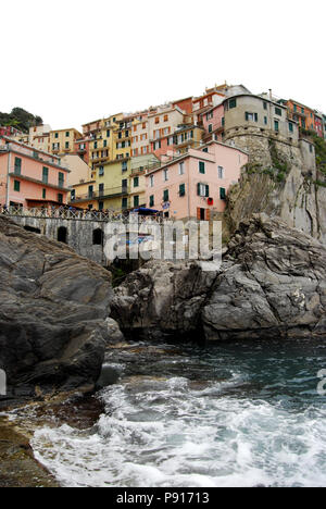Low angle looking up from harbour to the colourful buildings of Manarola, Cinque Terre, Italy Stock Photo