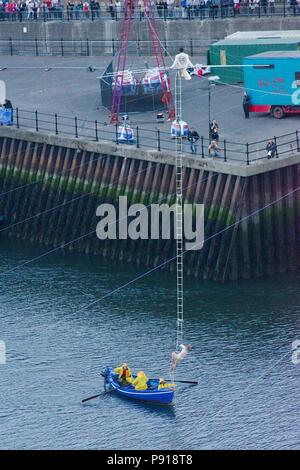 Sunderland, England, 13 July 2018. Chris Bullzini sitting on the inclined high wire as Johanne Humblet climbs a ladder from a boat to join him on his record breaking walk across the River Wear from the quayside to Wearmouth Bridge, part of Cirque Bijou’s performance “Portolan”. Credit: Colin Edwards/Alamy Live News. Stock Photo