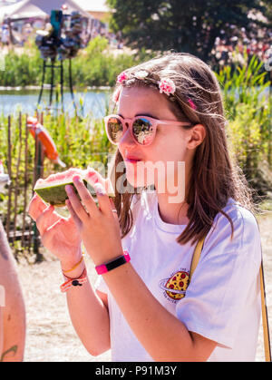 Young festival goer eating watermelon at Latitude Festival, Henham Park, Suffolk, England, 14th July, 2018 Stock Photo