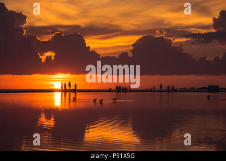 Fort Myers Beach during a sunset. the sky is reflected on a large puddle that accumalates on the beach sand after it rains. Stock Photo