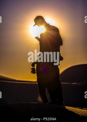 Man using phone in sand dunes Stock Photo