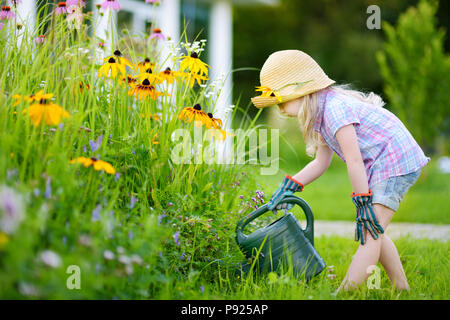 Cute little girl watering flowers in the garden at summer day Stock Photo