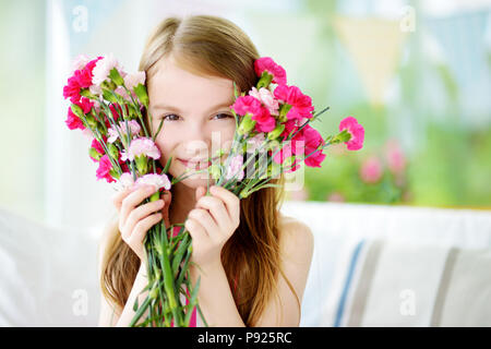 Adorable smiling little girl holding flowers for her mom on mother's day Stock Photo