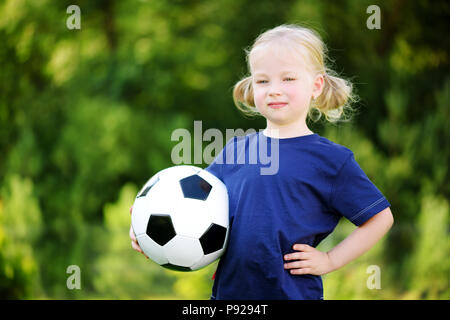 Cute little soccer player having fun playing a soccer game on sunny summer day Stock Photo