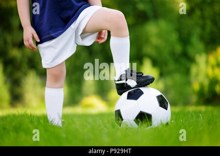 Close-up of a child having fun playing a soccer game on sunny summer day. Sport activities for children. Kids in sports uniform. Stock Photo