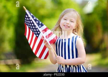 Adorable little girl holding american flag outdoors on beautiful summer day. Independence Day concept. Stock Photo