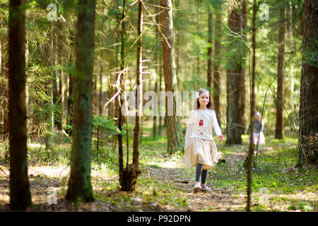 Adorable little girls picking the first flowers of spring in the woods on beautiful sunny spring day. Cute children having fun outdoors. Stock Photo