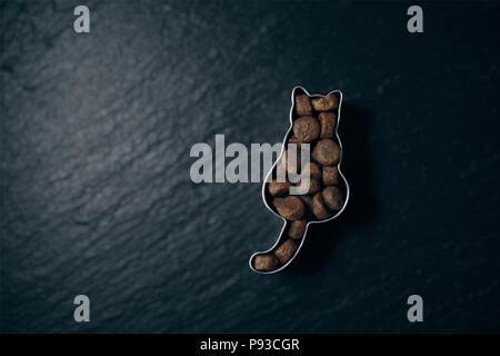 Dry food in a cat s haped cookie cutter on a slate - soft focus technique. Stock Photo