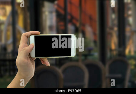 Woman hand shows mobile smartphone and blurred background - mockup template Stock Photo