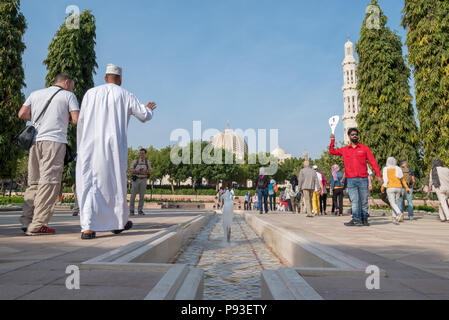 Tour guides and visitors entering the Sultan Qaboos Grand Mosque in Muscat, Oman Stock Photo