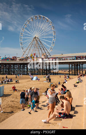 UK, England, Lancashire, Blackpool, vistors relaxing in sunshine on sea wall steps by Central Pier Stock Photo