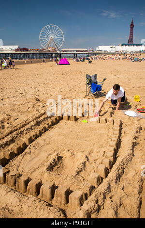 UK, England, Lancashire, Blackpool, beach adult visitor making sandcastle by Central Pier Stock Photo