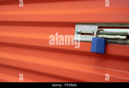 Blue plastic lock on an orange self storage unit door. Stock Photo