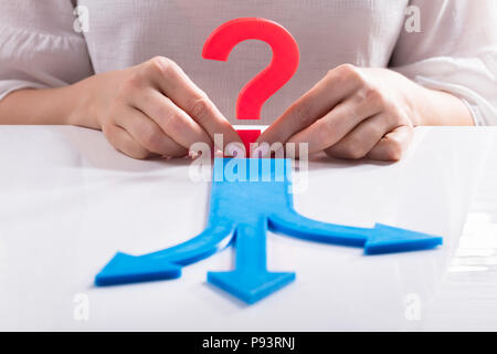 Blue Arrows Showing Various Directions In Front Of Woman's Hand Holding Question Mark Sign Stock Photo