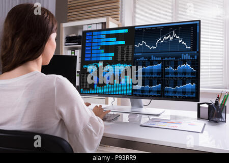 Female Stock Market Broker Analyzing Graphs On Computer At Workplace Stock Photo