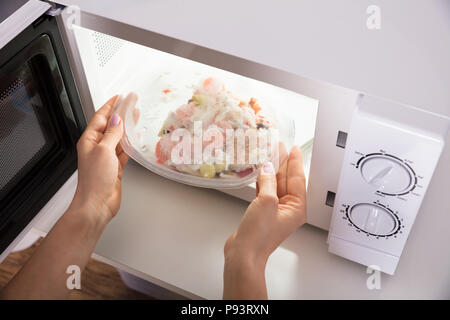 Cooking, heating food in the microwave. Baked potatoes with meat,  vegetables on a white plate in the microwave top view Stock Photo - Alamy