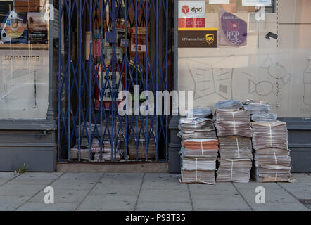 Read all about it! Todays newspapers stacked outside a newsagents early on a Saturday morning.  Colchester, Essex, UK Stock Photo