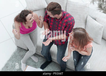 triumphant group of friends laughing while sitting on the couch in the living room Stock Photo