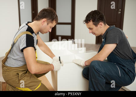 Service of assembly furniture. Two carpenters work on assemble wardrobe Stock Photo