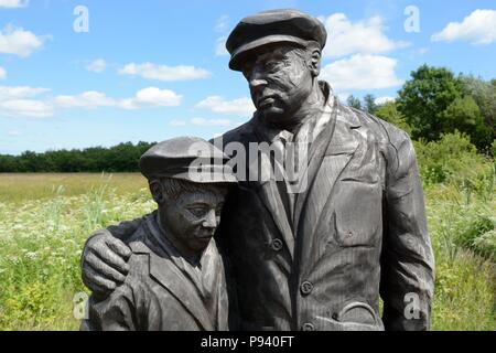 Wooden sculpture of a coal miner  father and son at Parc Slip Nature Reserve reclaimed colliery 112 men and boys lost their lives Aberkenfig Wales Stock Photo