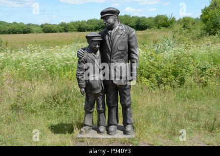 Wooden sculpture of a coal miner  father and son at Parc Slip Nature Reserve reclaimed colliery 112 men and boys lost their lives Aberkenfig Wales Stock Photo
