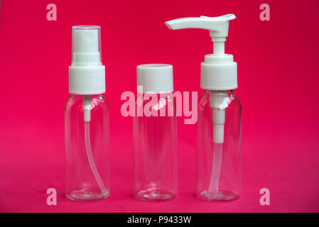 Set of empty small traveling cosmetics bottles on pink background. For soap, shampoo, shower gel, spray Stock Photo