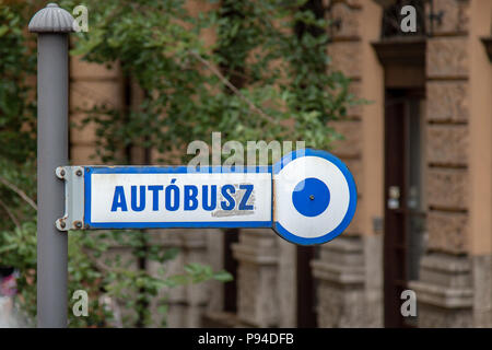 A blue and white bus stop sign that says autobusz in Hungarian in Budapest. Stock Photo