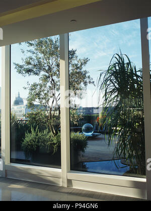 View through glass patio doors of trees and shrubs on city roof terrace Stock Photo