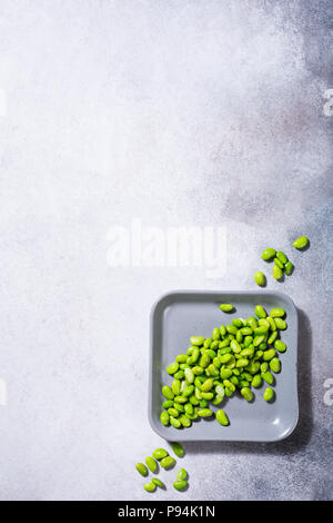 Green fresh soybeans on gray square plate on concrete background. Healthy food concept flat lay with coppy space. Top view. Stock Photo
