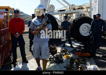 A guest touring the aircraft  carrier USS Ronald Reagan (CVN 76) dons part of a firefighting ensemble during a demonstration by the ship's crash and salvage team. Ronald Reagan, 'America's Flagship,' is participating in the annual Coronado Speed Festival. This event was created in 1997, to honor the military while enjoying a rich automobile history. For two days, Naval Base Coronado and hosting ships opens its gates to the public for open house. (U.S. Navy Stock Photo